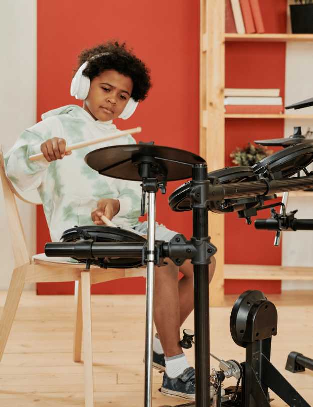 A colored kid playing an electric drum set.