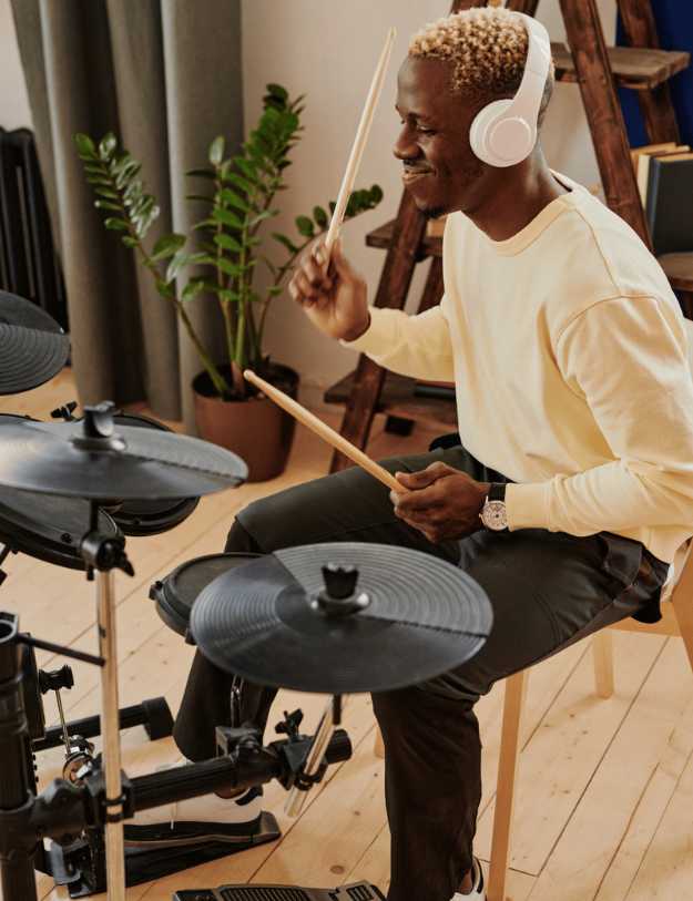 A colored man playing an electric drum set.