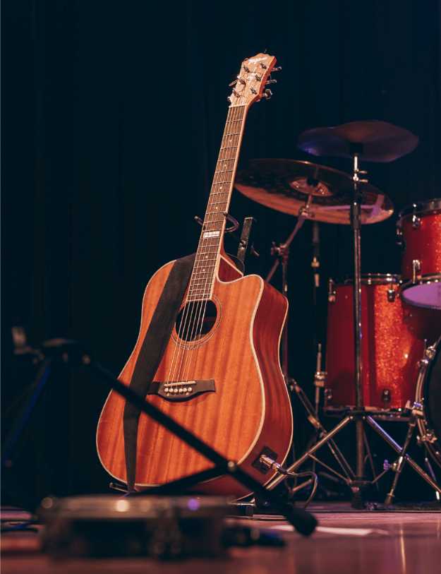 A acoustic guitar on stage with other instruments.