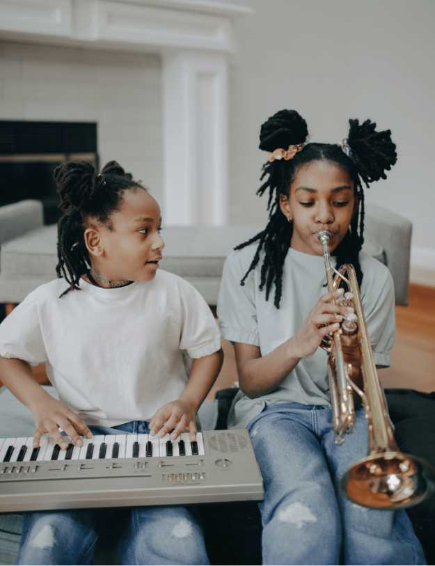 Two colored girls playing instruments together in a Livingroom 