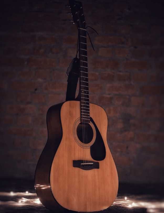 Beautiful acoustic guitar standing up with brick wall background