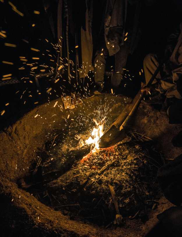 In the dark as someone breaks apart burning fire with a camping shovel.