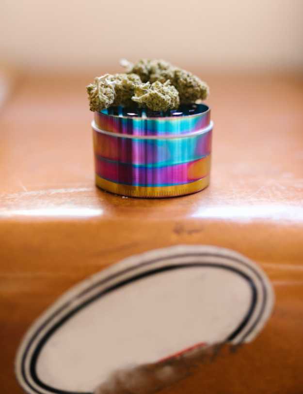 A weed grinder that is open with full buds on top