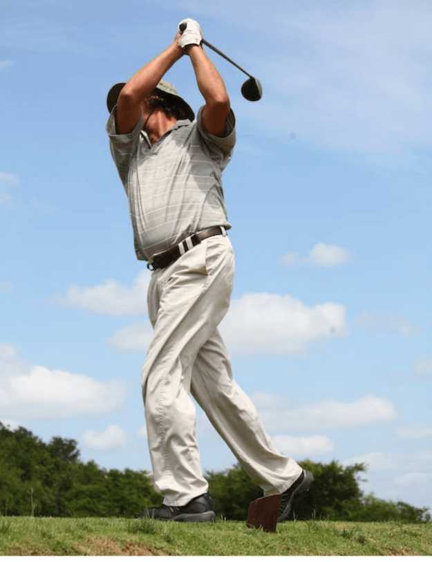 An Older man in mid swing on the golf course