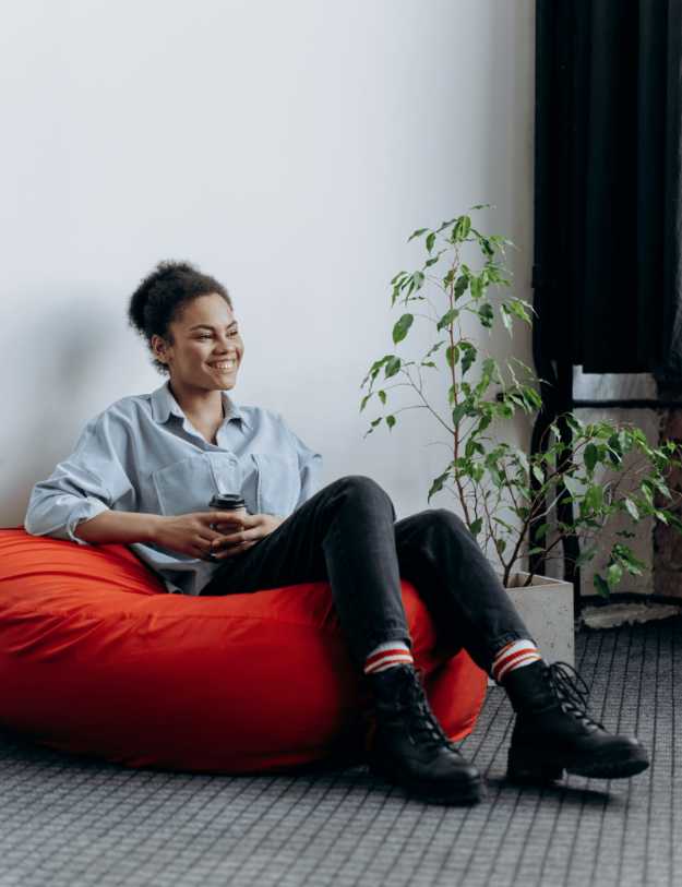 A colored woman sitting on a red bean bag chair.