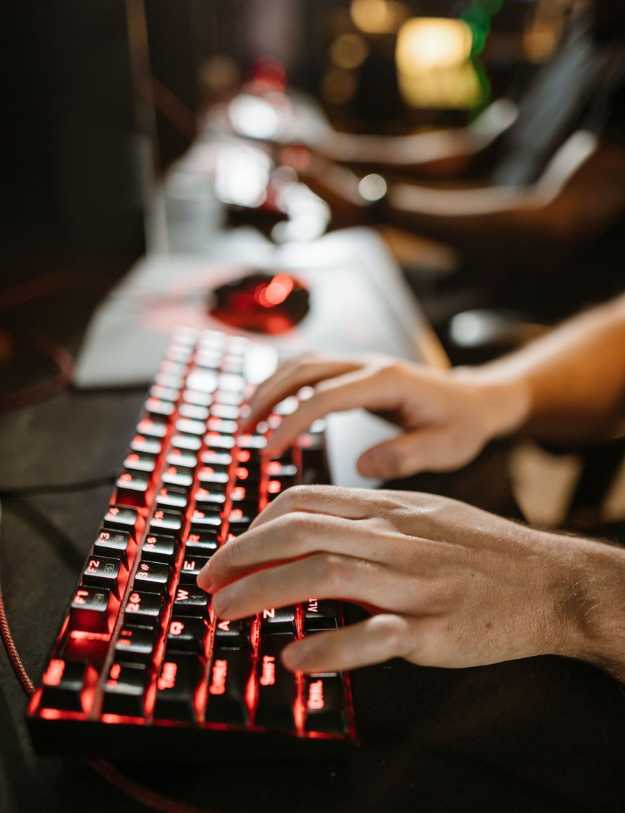 Someone typing on a red light up keyboard.
