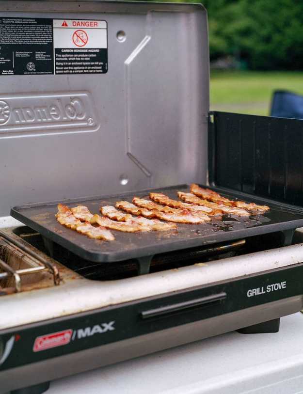 Bacon being grilled on a griddle grill.