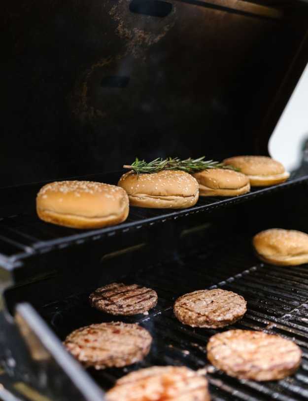 Burgers being grilled with their buns.