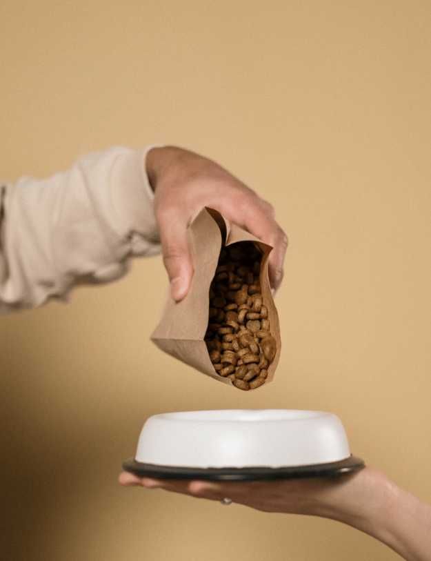  Someone pouring dog food into a bowl.