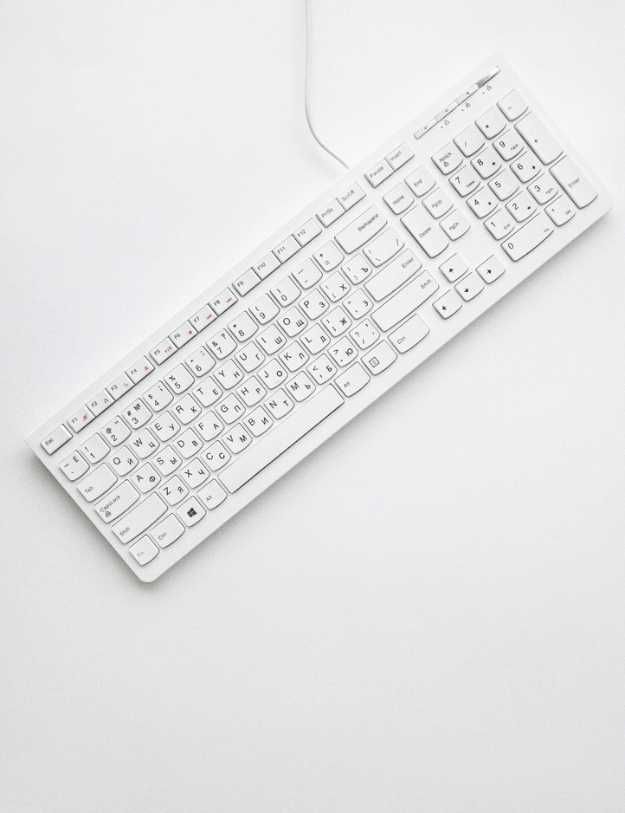 A white keyboard on a white desk.