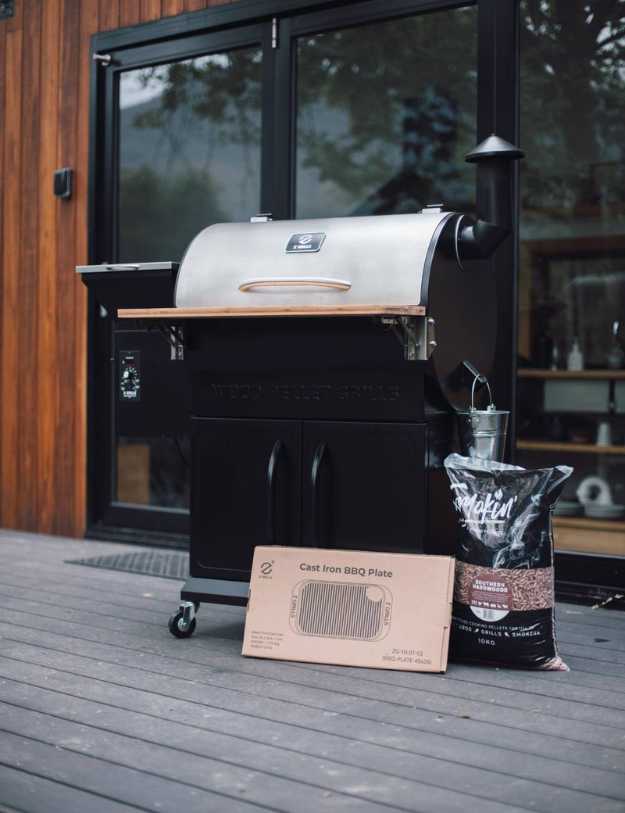 A Grill outside on a porch with woodchips and a cardboard box flattened.