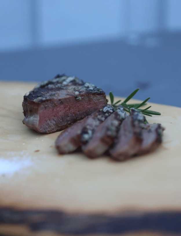 Sliced steak on a wood cutting board.